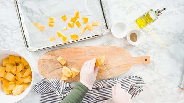 Flat lay. Cutting butternut squash on a wood cutting board.