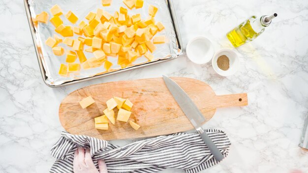 Flat lay. Cutting butternut squash on a wood cutting board.