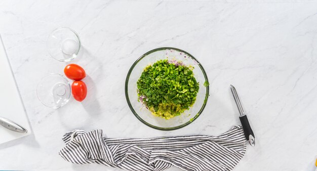 Flat lay. Cutting ingredients on a white cutting board to make classic guacamole dip.