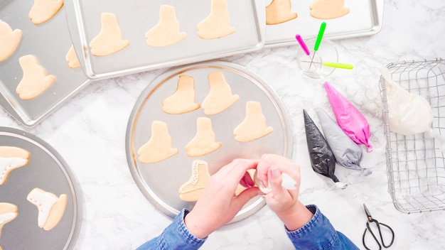 Flat lay. Decorating ice skate shaped sugar cookies with white color royal icing.