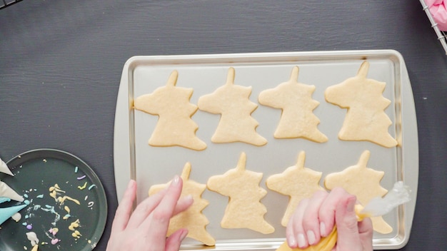 Flat lay. Decorating unicorn sugar cookies with multi-color royal icing.