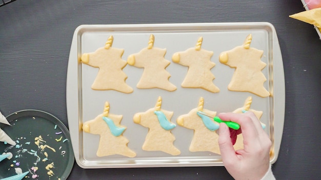 Flat lay. Decorating unicorn sugar cookies with multi-color royal icing.