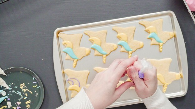 Flat lay. Decorating unicorn sugar cookies with multi-color royal icing.