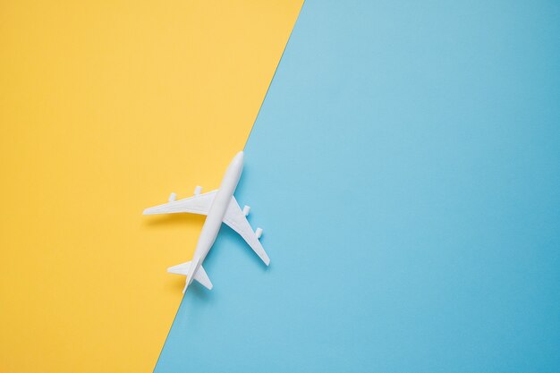 Flat lay design of travel concept with plane on blue and yellow 