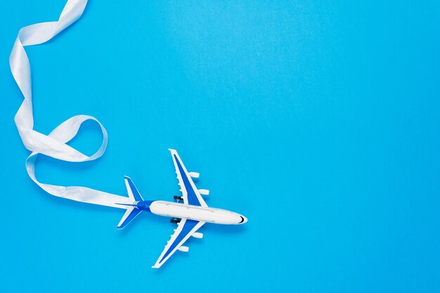 Flat lay design of travel concept with a plane on blue