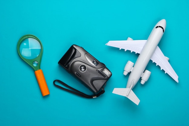Flat lay design of travel concept with plane, camera and magnifier.