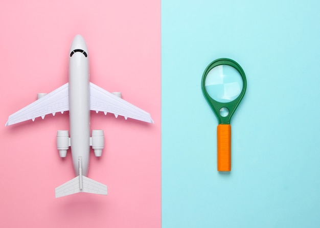 Flat lay design of travel concept with plane and magnifier.