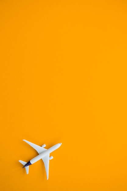 Flat lay design of travel concept with plane on yellow background