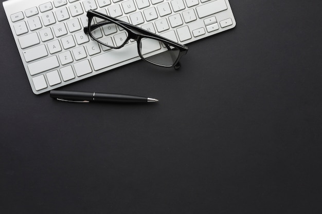 Flat lay of desktop with glasses and keyboard