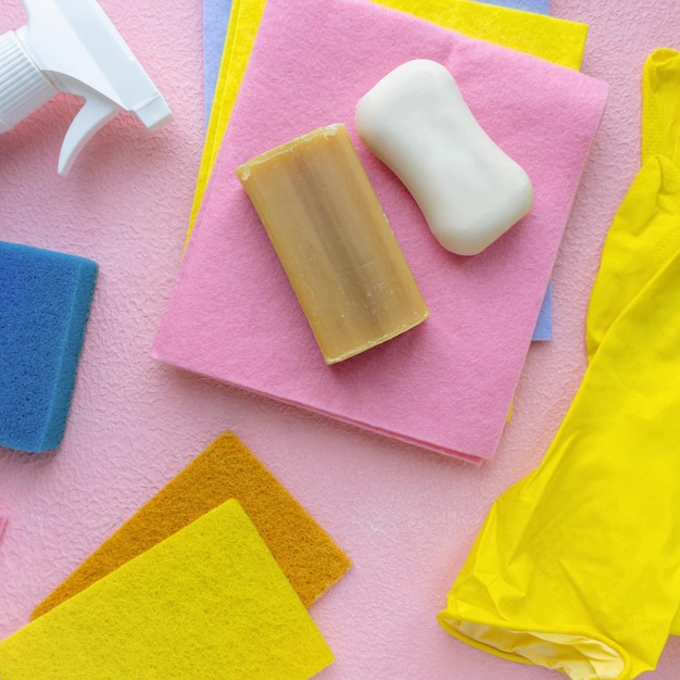 Flat lay of detergents and cleaning items on pink background, top view.