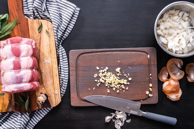 Flat lay. Dicing onion and garlic to season boneless pork roast.