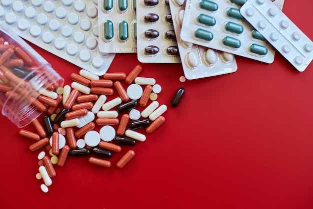 Flat lay different colorful Medical pills on red background