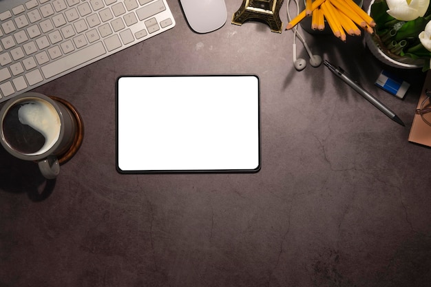 Плоский цифровой планшет с чашкой кофе с пустым экраном и канцелярскими принадлежностями на черном столе Современное рабочее место