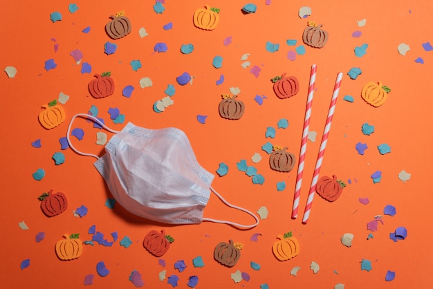 Photo flat lay of diy pumpkins of autumn colors on orange desk and facial mask