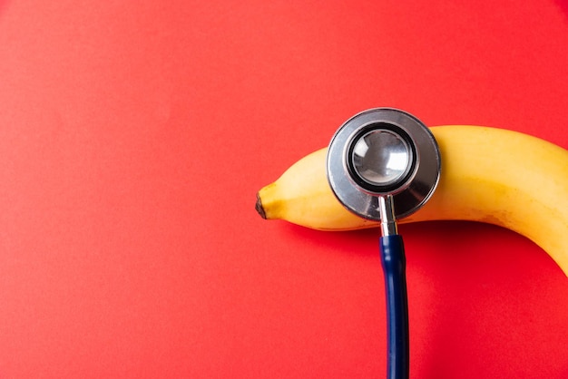 Disposizione piatta di stetoscopio medico e banana gialla