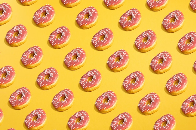 Flat lay of donuts and shadows pattern on yellow.