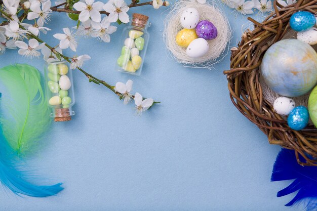 Flat lay easter eggs in nest and glass bottles on a blue