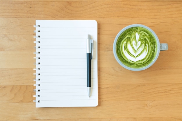 Плоская кладка пустой записной книжки и чашки горячего зеленого чая латте