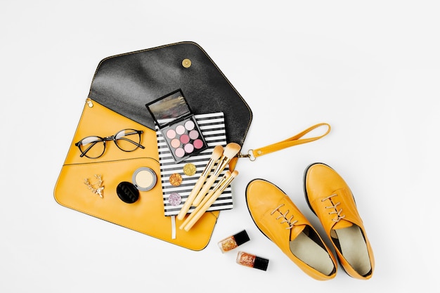 Photo flat lay of female fashion accessories, shoes, makeup products and handbag on orange colors. beauty and fashion concept