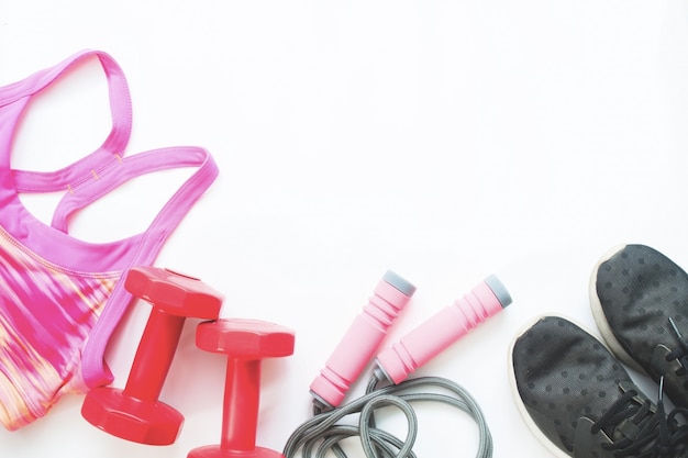 Flat lay of female sport equipments in pink and red color with black sneaker on white background