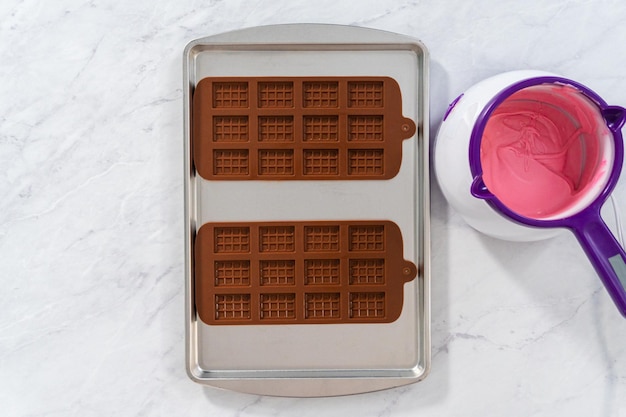 Disposizione piatta. farcire lo stampo per cioccolato in silicone con cioccolato fuso per realizzare dei mini cioccolatini rosa.