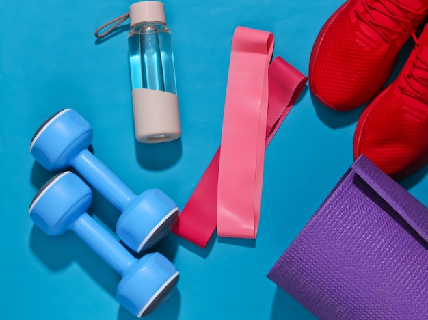 Photo flat lay fitness composition. sports equipment on a bright blue background with deep shadow.