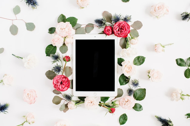 flat lay floral frame with tablet, red and beige rose flower buds on white