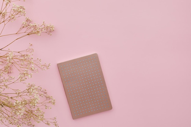 Плоские цветы и дневник на розовом фоне, вид сверху, макет