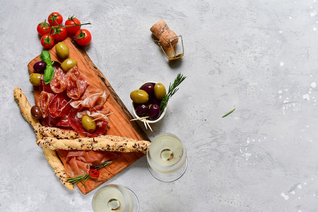 Flat lay food. Traditional Italian snacks for aperitif : salami, bresaola, prosciutto, olives.  and two glasses prosecco