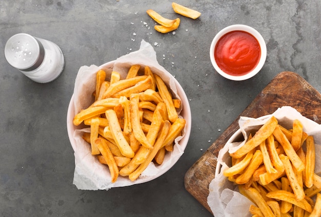 Photo flat lay of french fries with ketchup and salt shaker