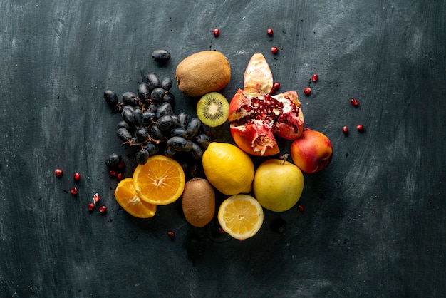 Flat lay fresh fruit selectrion layout on a grunge surface such as grapes, kiwi, orange, exotic tropical fruit