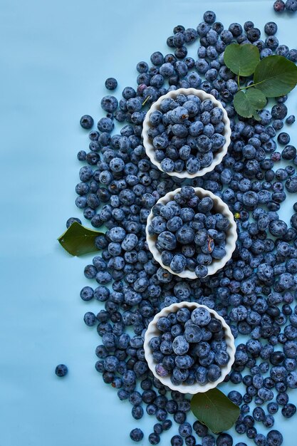 Disposizione piatta di mirtilli succosi organici freschi in una ciotola su sfondo blu vista dall'alto spazio copia concetto di alimentazione sana e dieta antiossidante vitamina cibo estivo