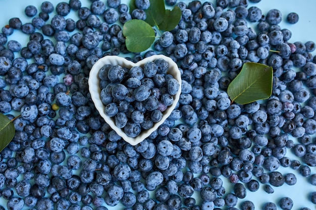 Flat lay of fresh organic juicy blueberries in a bowl on blue background top view copy space Concept of healthy and dieting eating antioxidant vitamin summer food