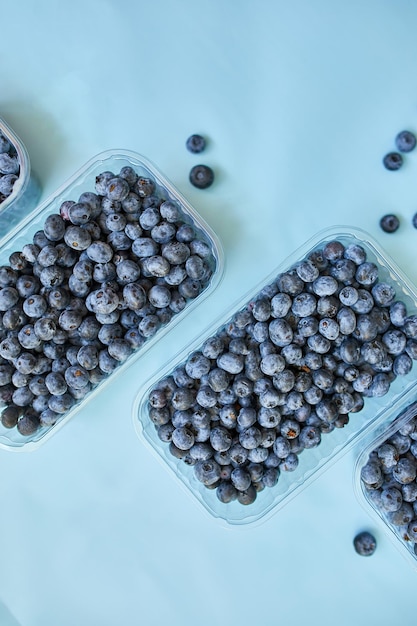 Flat lay of fresh organic juicy blueberries in a box on blue background top view copy space Concept of healthy and dieting eating antioxidant vitamin summer food