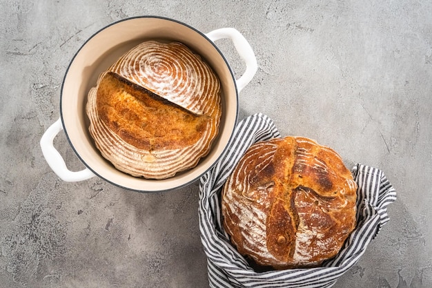 Flat lay Freshly baked loaf of a wheat sourdough bread with marks from bread proofing basket in enameled cast iron dutch oven