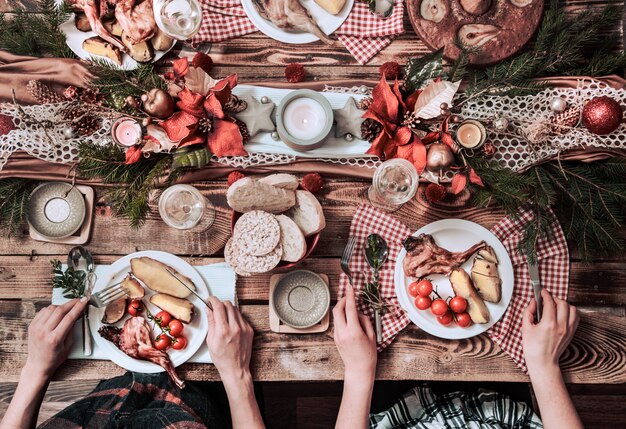 Flat-lay of friends hands eating and drinking together. Top view of people having party, gathering, celebrating together at wooden rustic table