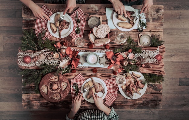 Flat-lay of friends hands eating and drinking together. Top view of people having party, gathering, celebrating together at wooden rustic table