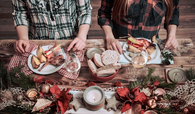 Flat-lay of friends hands eating and drinking together. Top view of people having party, gathering, celebrating together at wooden rustic table