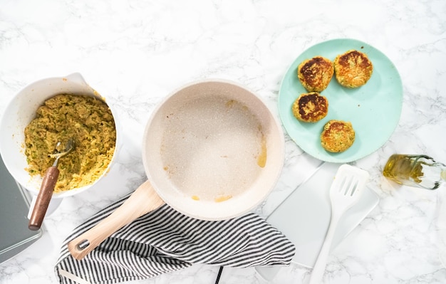 Flat lay. Frying zucchini cakes in olive oil on a frying pan.