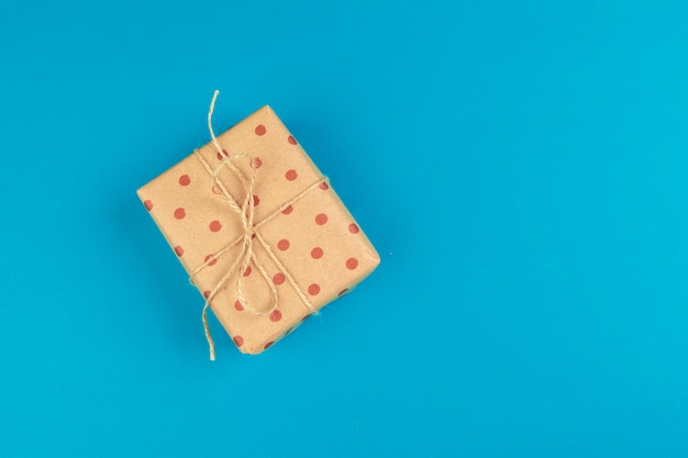 Flat lay of gift box decorated with bow on blue background