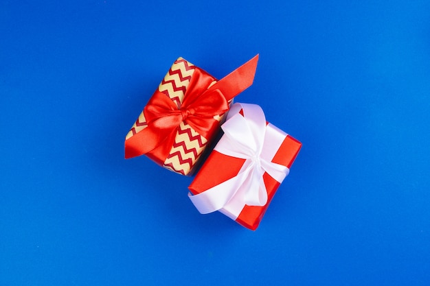 Flat lay of gift box decorated with bow on blue  