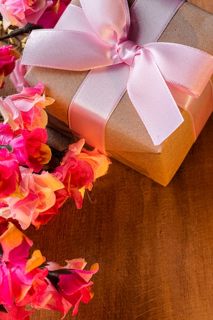 Foto piatto di laici regalo con nastro rosa con fiori sul tavolo di legno