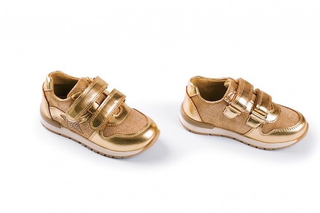 Distesi. le scarpe sportive per bambini d'oro isolate su bianco