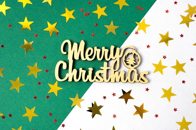 Flat lay of gold stars on christmas backgrounds with wood lettering. Merry Christmas and Happy Holidays greeting consept