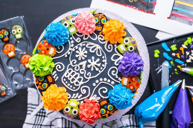 Flat lay. Gourmet Dia de los Muertos cake decorated with colorful buttercream frosting and gummy cupcake toppers.