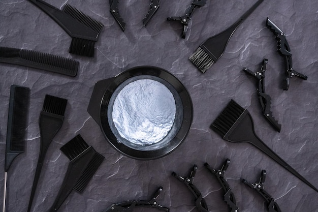 Flat lay. Hair color dye powder in a black plastic mixing bowl on a black background.