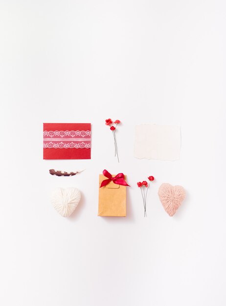 Flat lay of handmade envelope, gift, hearts, roses and feather for greeting card