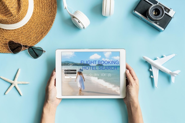 Disposizione piatta delle mani che tengono tablet e accessori da viaggio su sfondo blu concetto di vacanza estiva di viaggio copia spazio per la vista dall'alto del testo