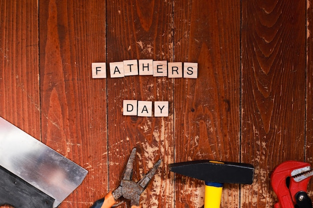 Flat lay happy father's day lined with letters Building tools on a wooden background Repair and construction