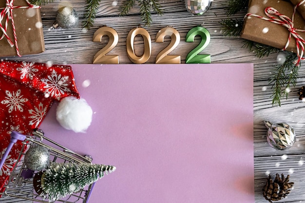 Photo flat lay happy new year greeting card with copy space very peri color, numbers 2022 and craft gifts with red christmas hat